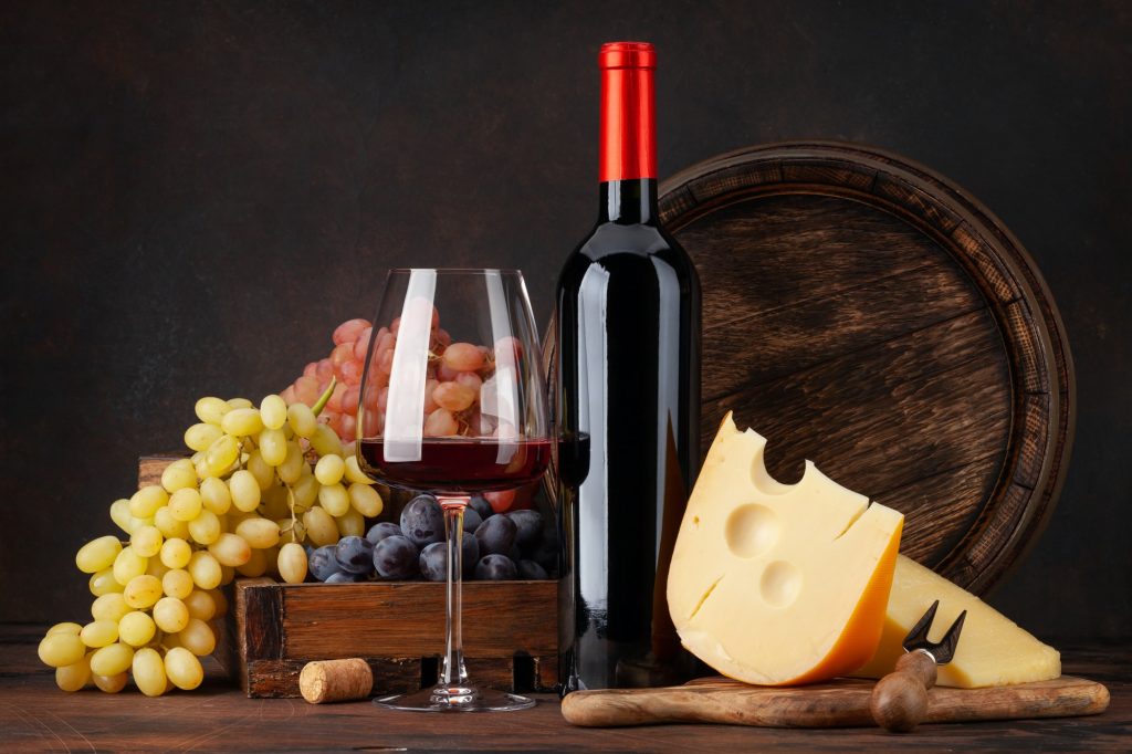 Wine bottle, grapes, cheese and glass of red wine